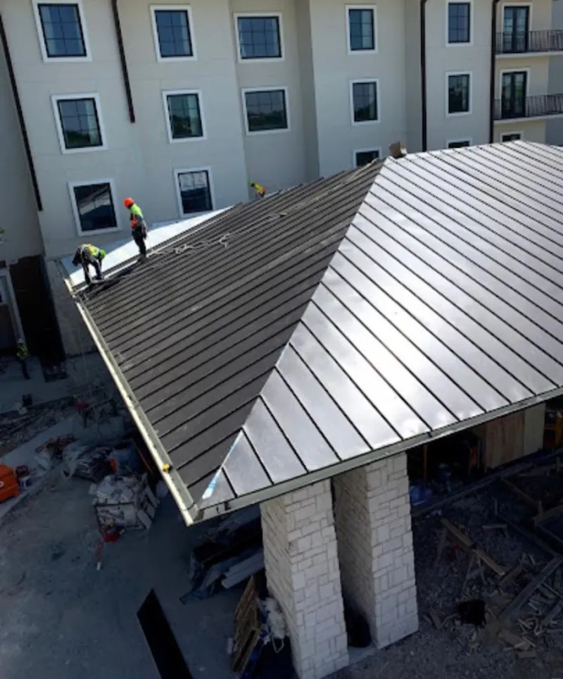 Crew installing standing seam metal roof panels on a commercial project in Olympia